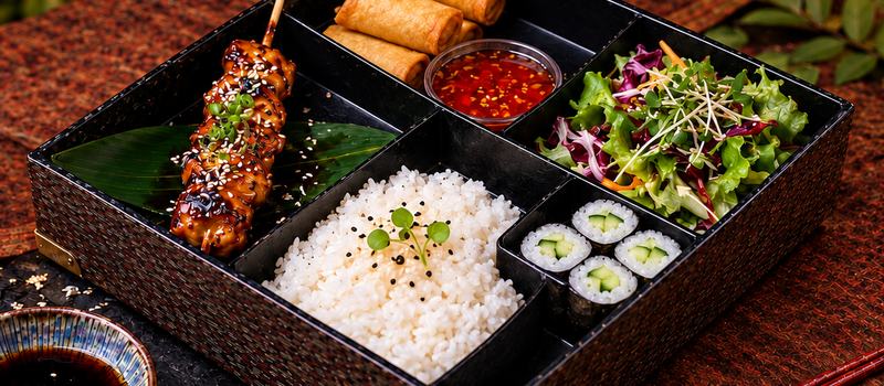 Bento med kycklingspett, vårrullar, ris och maki
